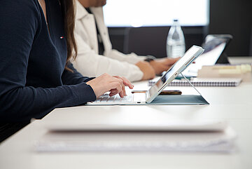 Studierende im Seminarraum mit Lehrmaterialien, Block und Laptop