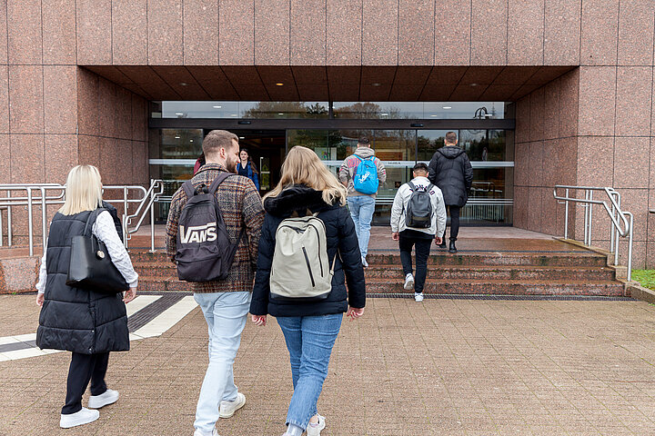 Junge Menschen mit Rucksäcken und Taschen auf dem Weg in die Hochschule der Bundesagentur für Arbeit