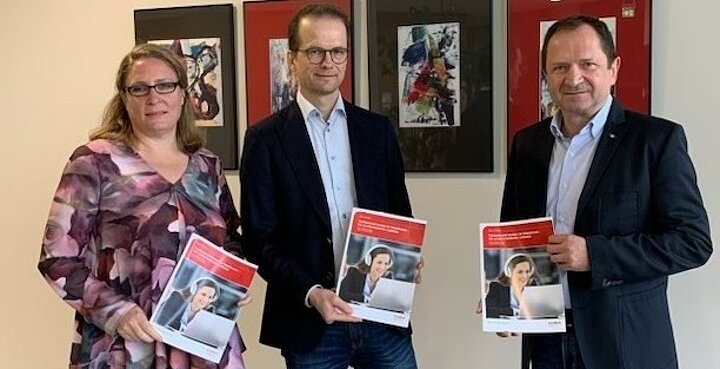 Prof. Dr. Matthias Rübner und Andrea Pintschka-Vögeli übergeben den Leitfaden „Professionell beraten im Videoformat“ an Prof. Dr. Andreas Frey  