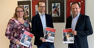 Prof. Dr. Matthias Rübner und Andrea Pintschka-Vögeli übergeben den Leitfaden „Professionell beraten im Videoformat“ an Prof. Dr. Andreas Frey  