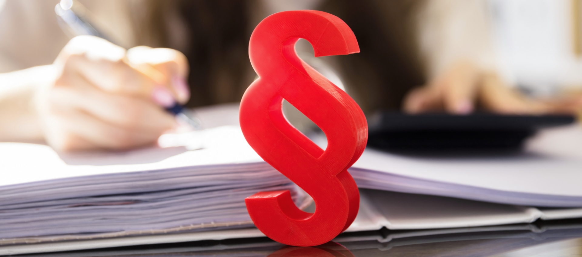 Rotes Paragraphen-Zeichen vor einem geöffneten Ordner Rotes Paragraphen-Zeichen vor einem geöffneten Ordner
